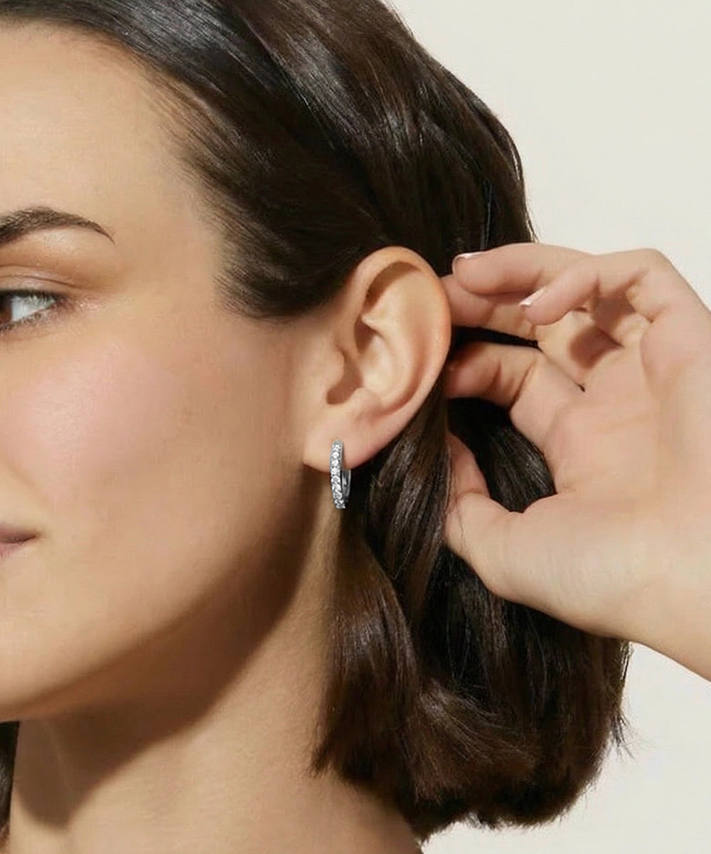 Close-up of a woman wearing a silver hoop earring with a neutral background