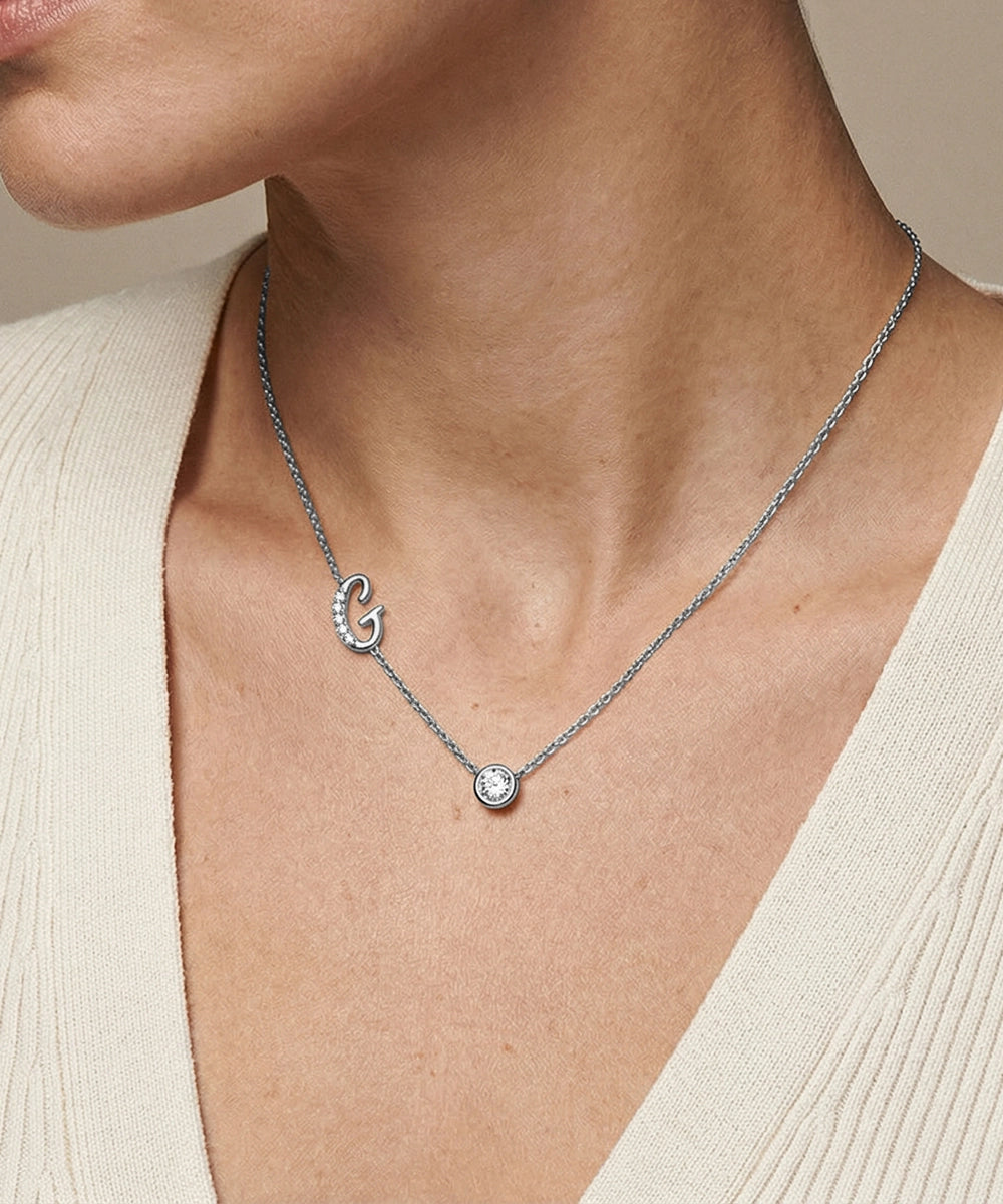 Necklace with a diamond pendant worn by a person, against a neutral background