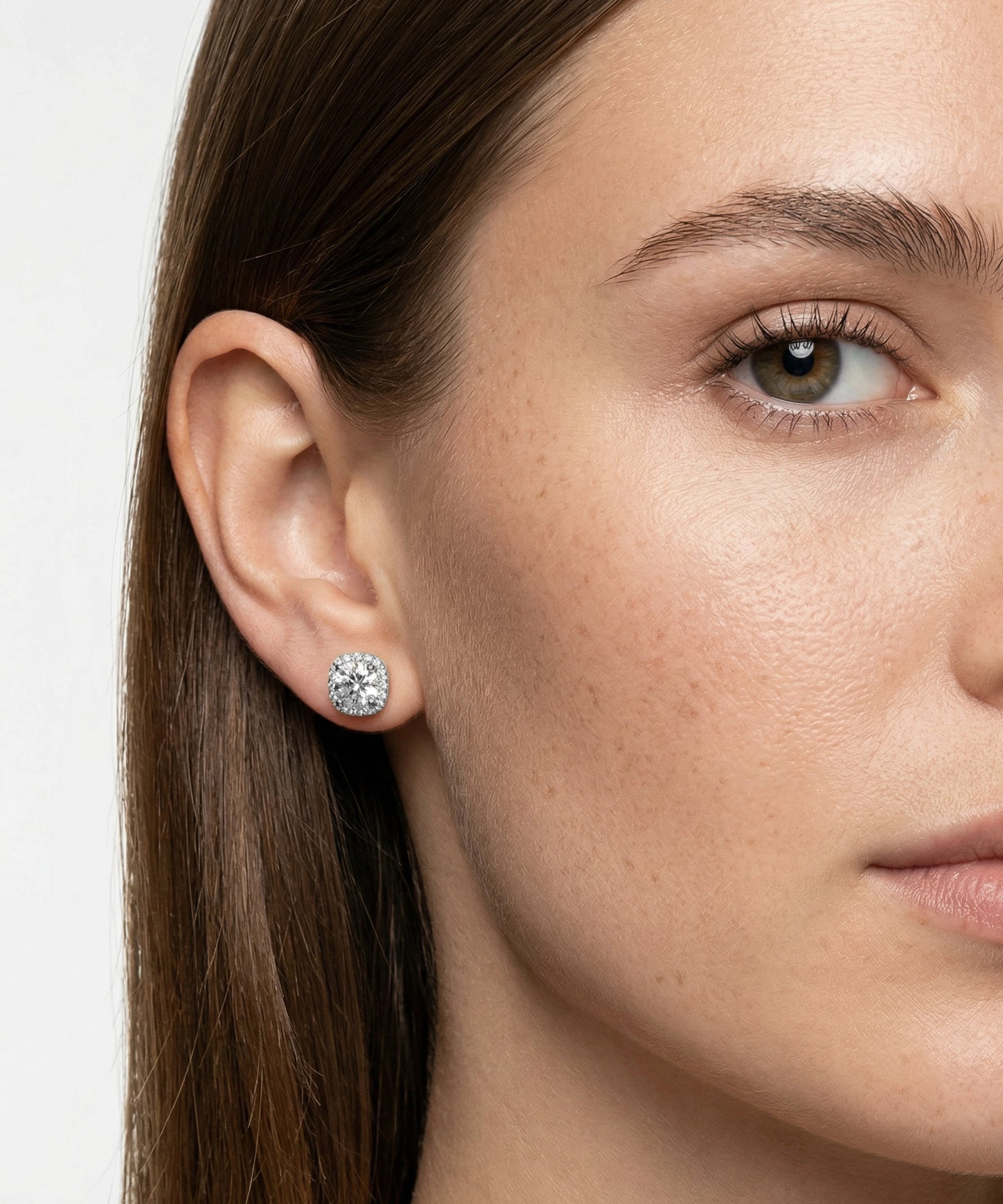 Close-up of a woman wearing a diamond earring with a plain background
