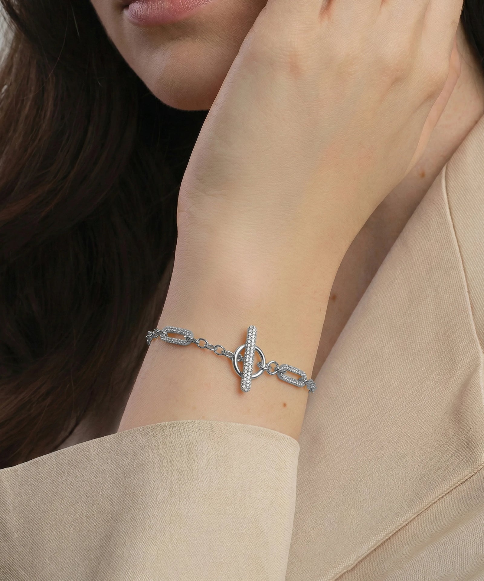 Close-up of a person wearing a silver bracelet on a beige sleeve.