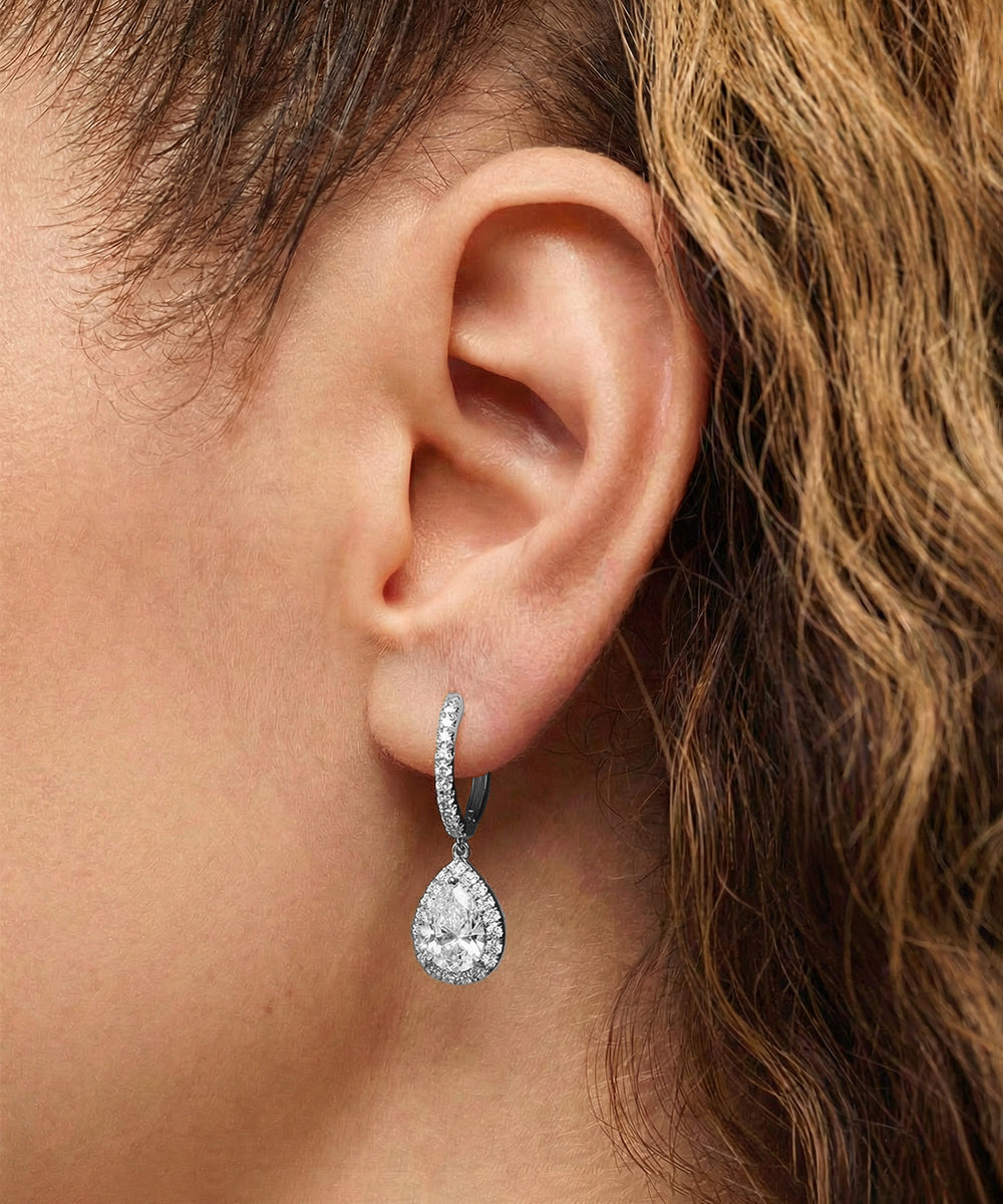 Teardrop-shaped earring worn by a person with brown hair.