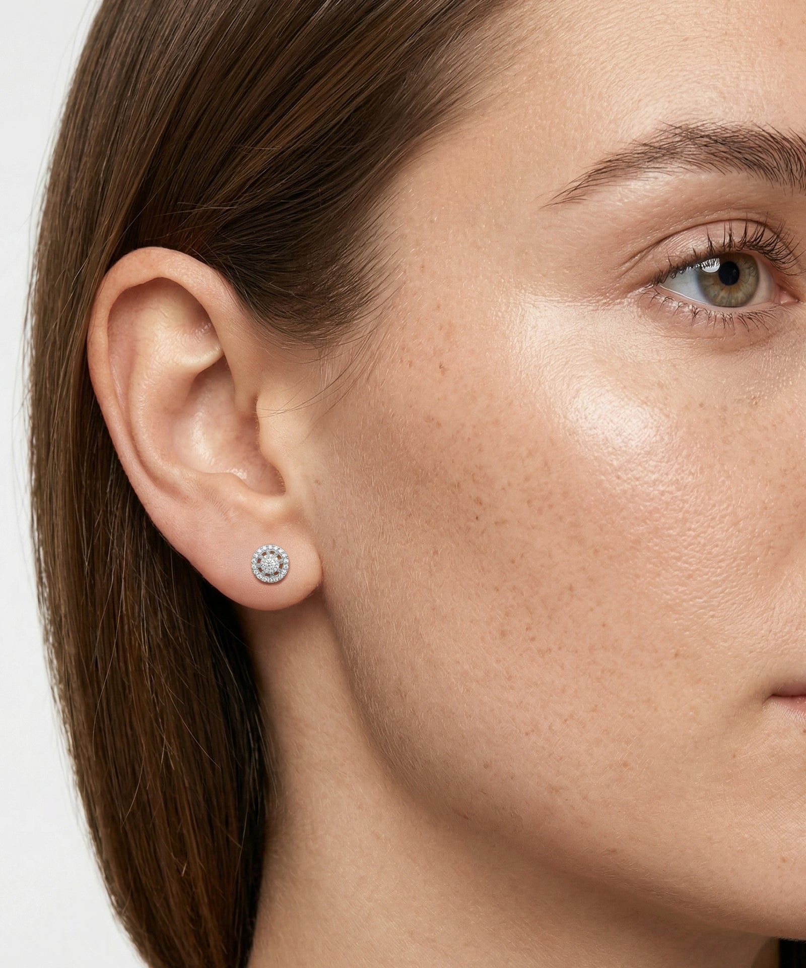 Close-up of a woman wearing a silver earring with a clear gemstone.