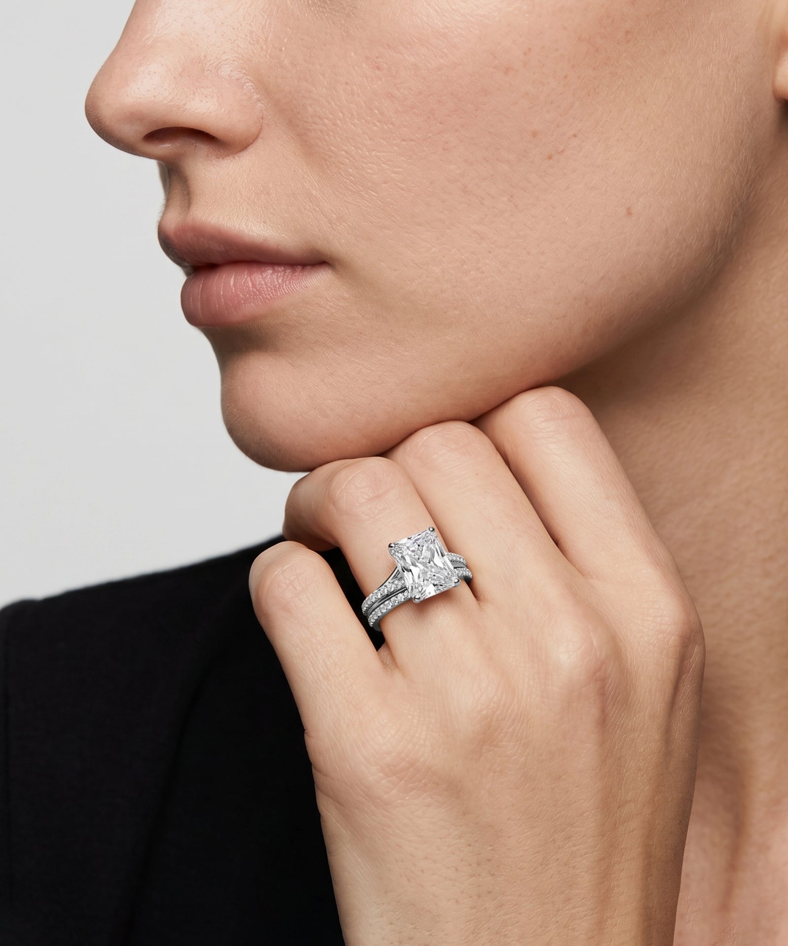 Radiant diamond engagement ring and matching pavé band on a model's hand.