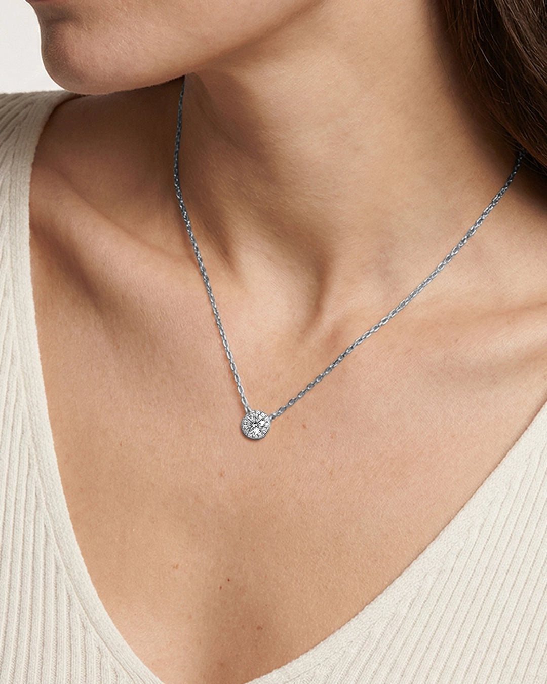 Silver necklace with a pendant on a person wearing a beige top