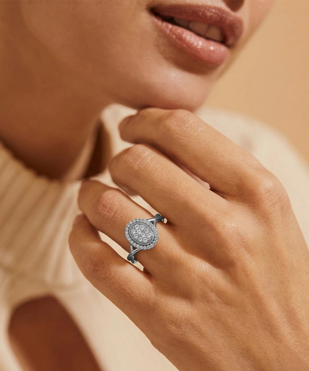 Close-up of a hand wearing a silver ring with a diamond on a neutral background