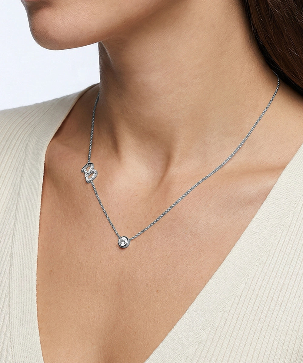 Necklace with two pendants on a person wearing a light-colored top.