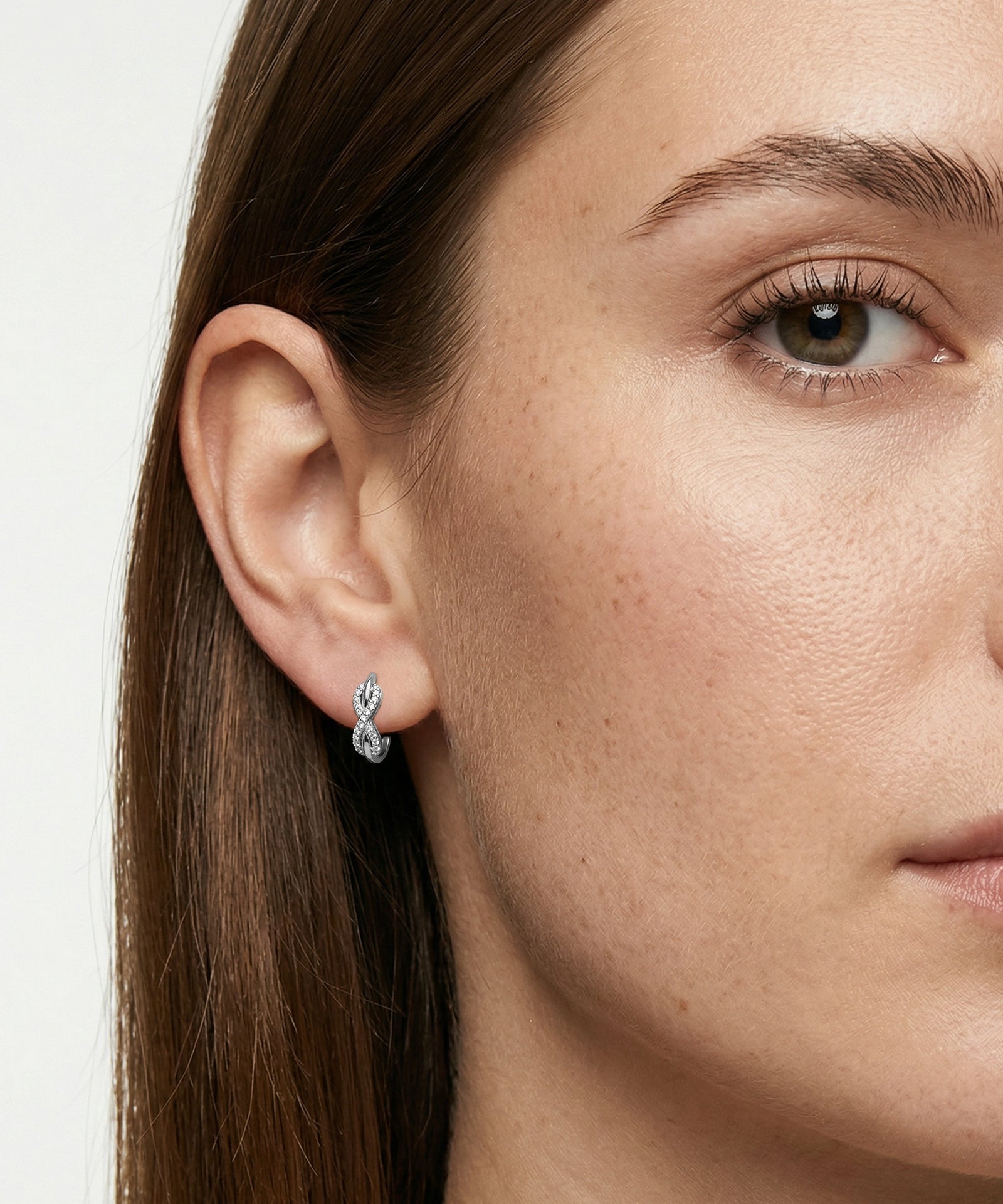 Close-up of a woman wearing diamond earrings with a plain background