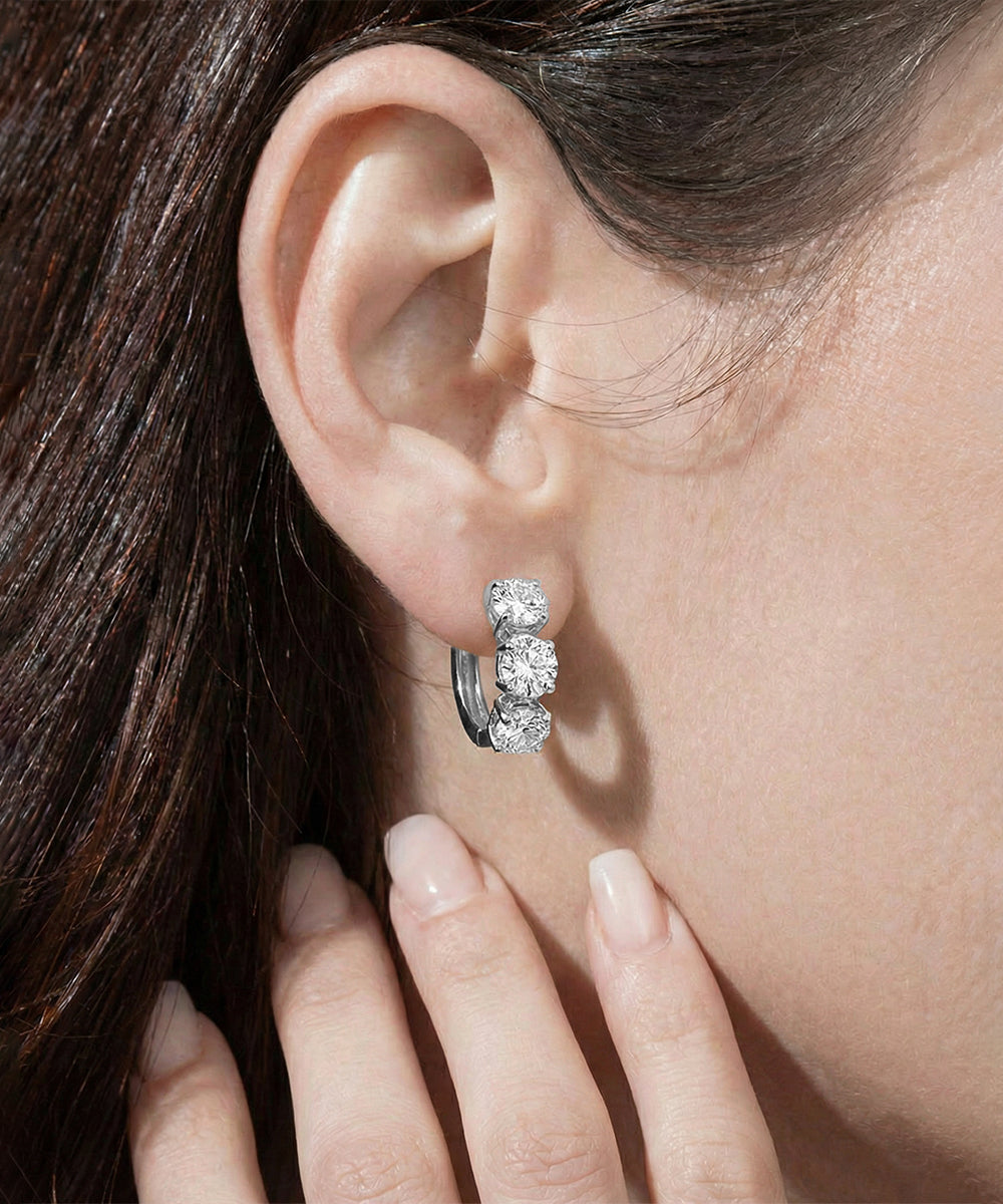 Close-up of a diamond earring worn by a person with dark hair.