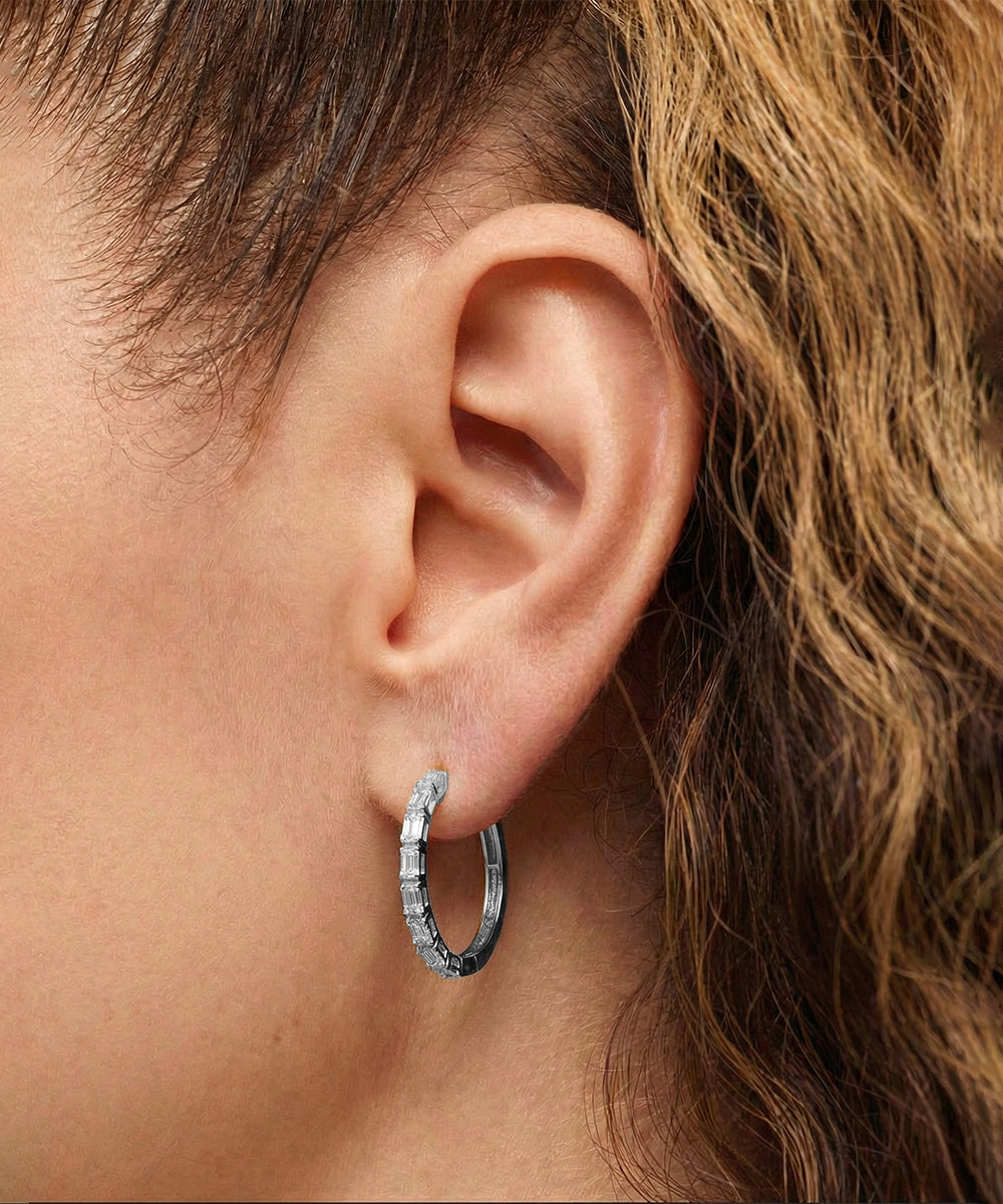 Close-up of an ear wearing a silver hoop earring with a blurred background