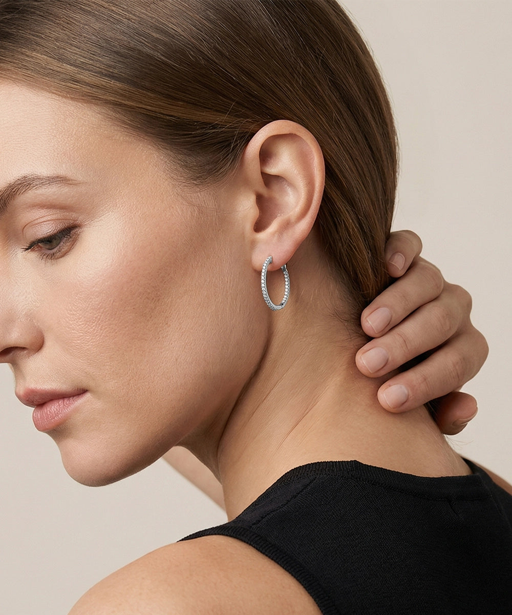 Close-up of a woman wearing a silver hoop earring with a neutral background