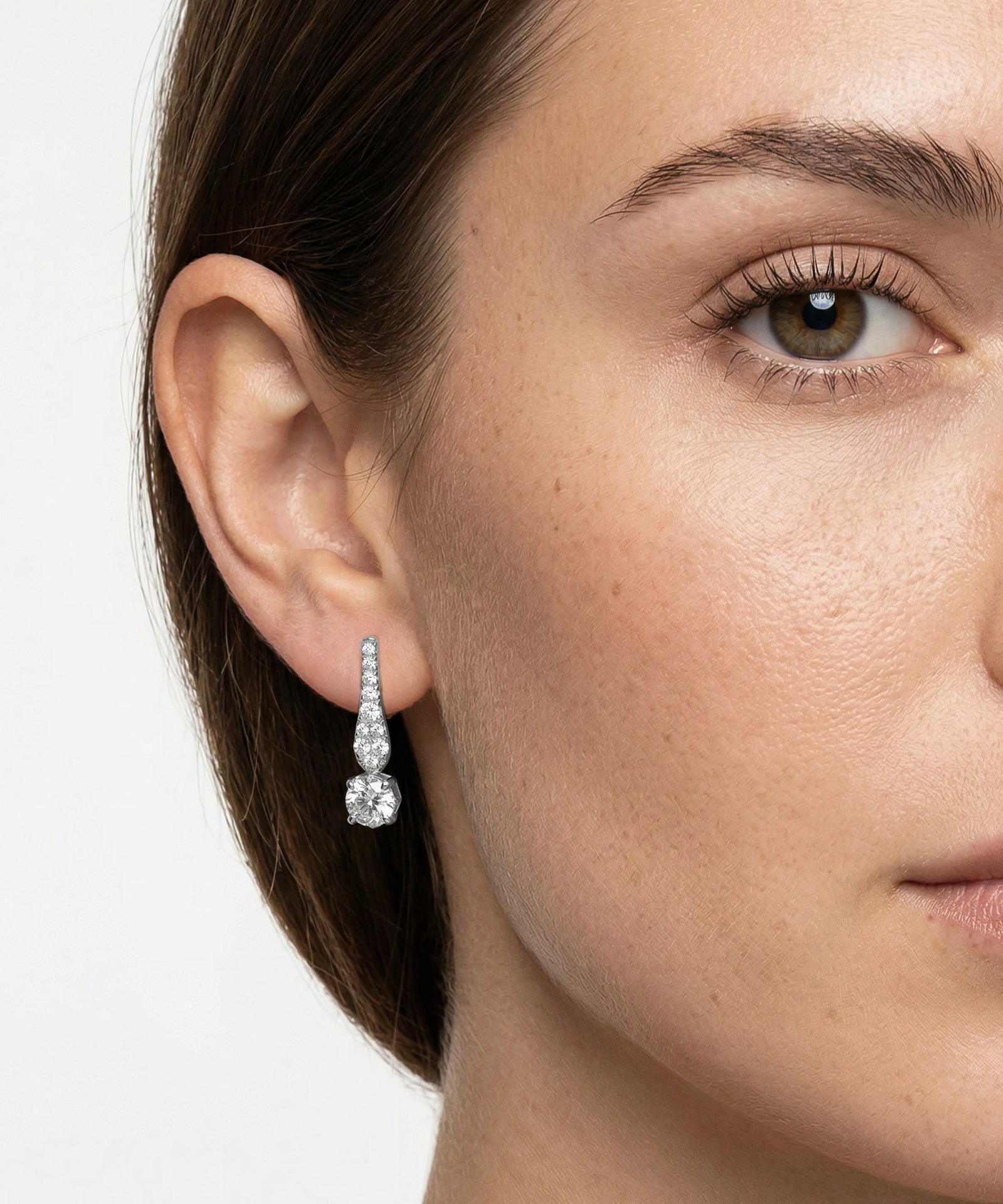Close-up of a woman wearing a diamond earring on a white background