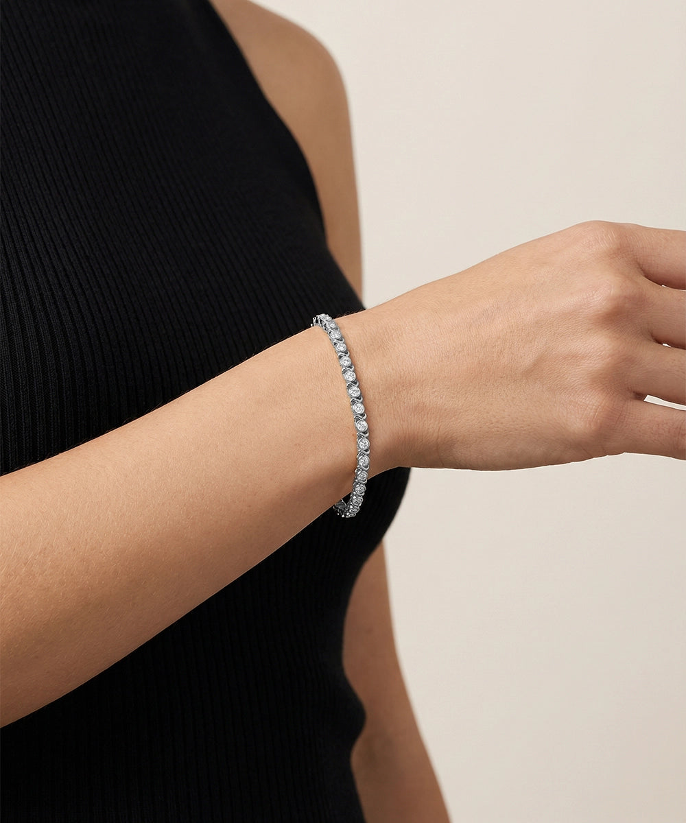 Gold bracelet on a person's wrist against a neutral background