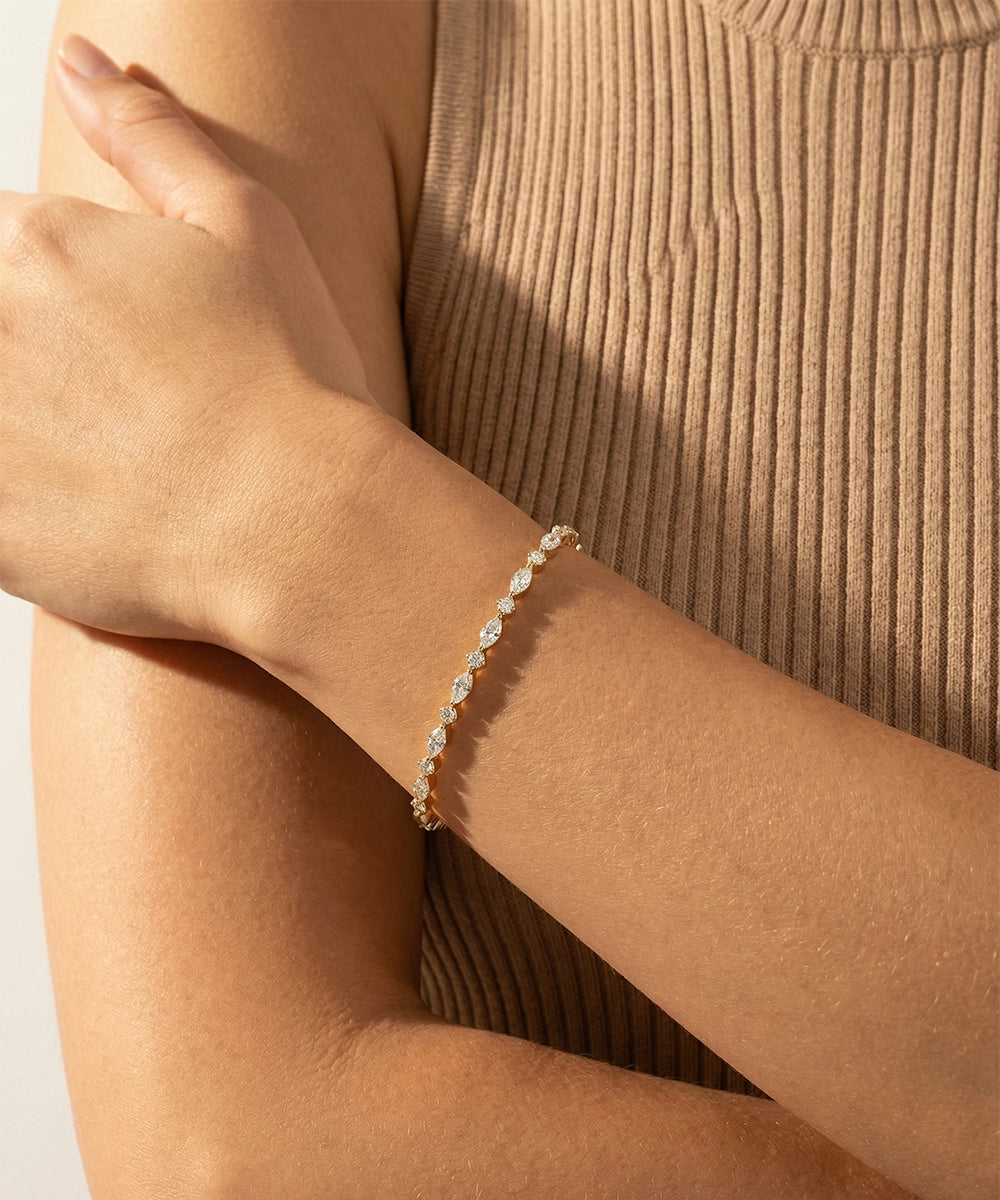 Close-up of a person wearing a delicate bracelet on a plain background