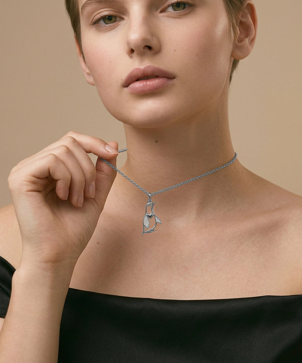 Woman wearing a necklace with a penguin pendant against a beige background