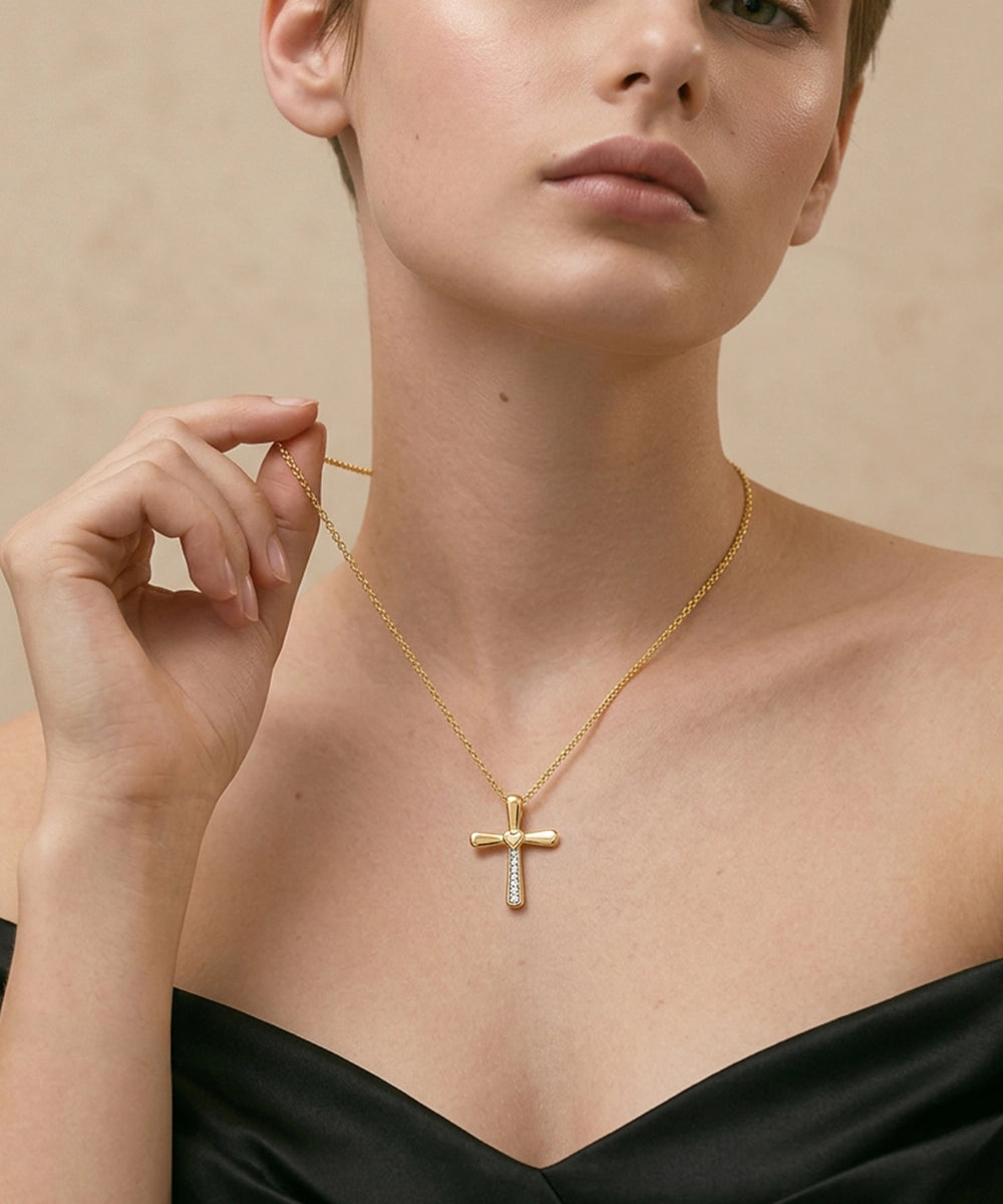 Woman wearing a gold necklace with a cross pendant on a beige background