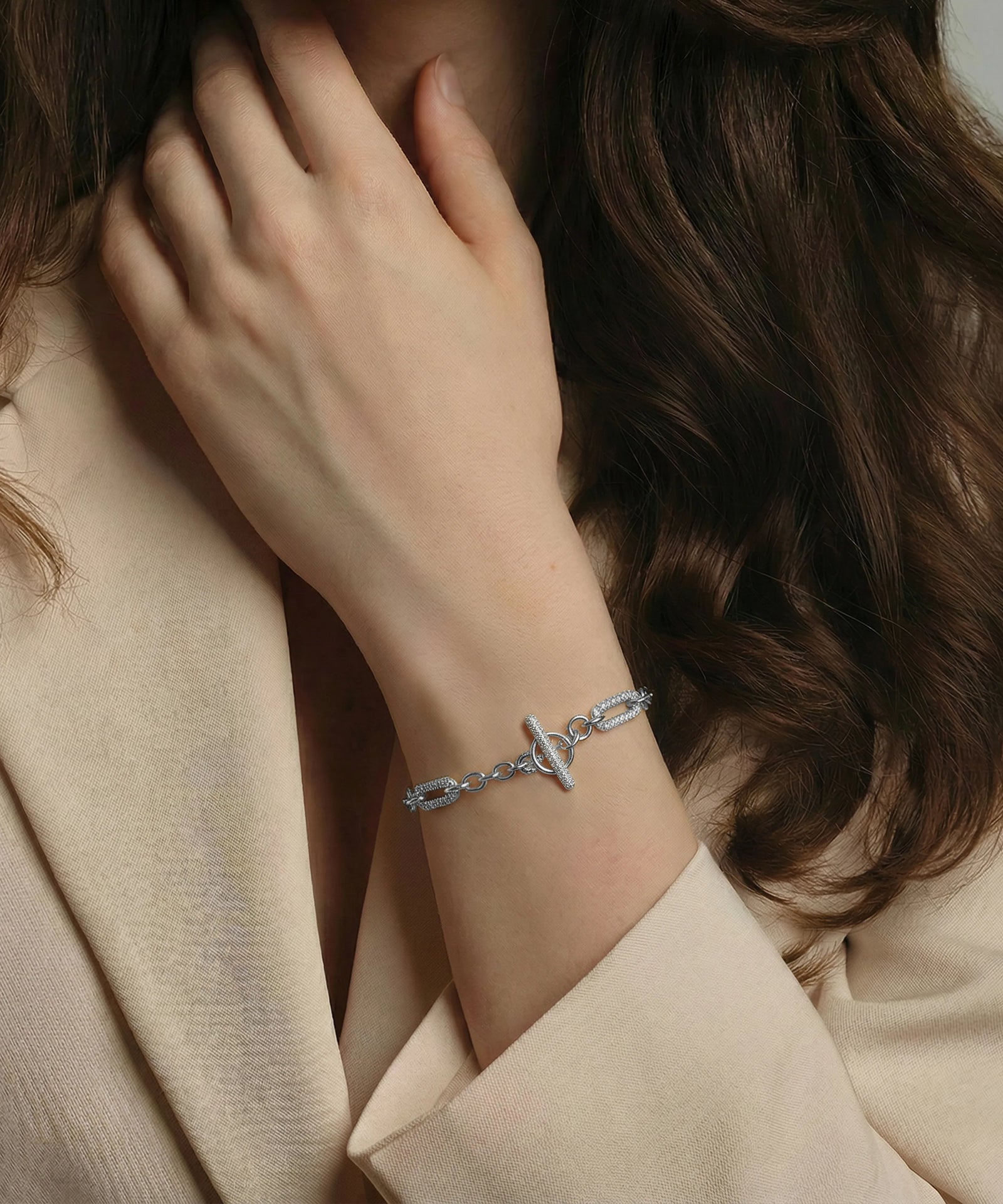 Close-up of a person wearing a silver bracelet with a neutral background