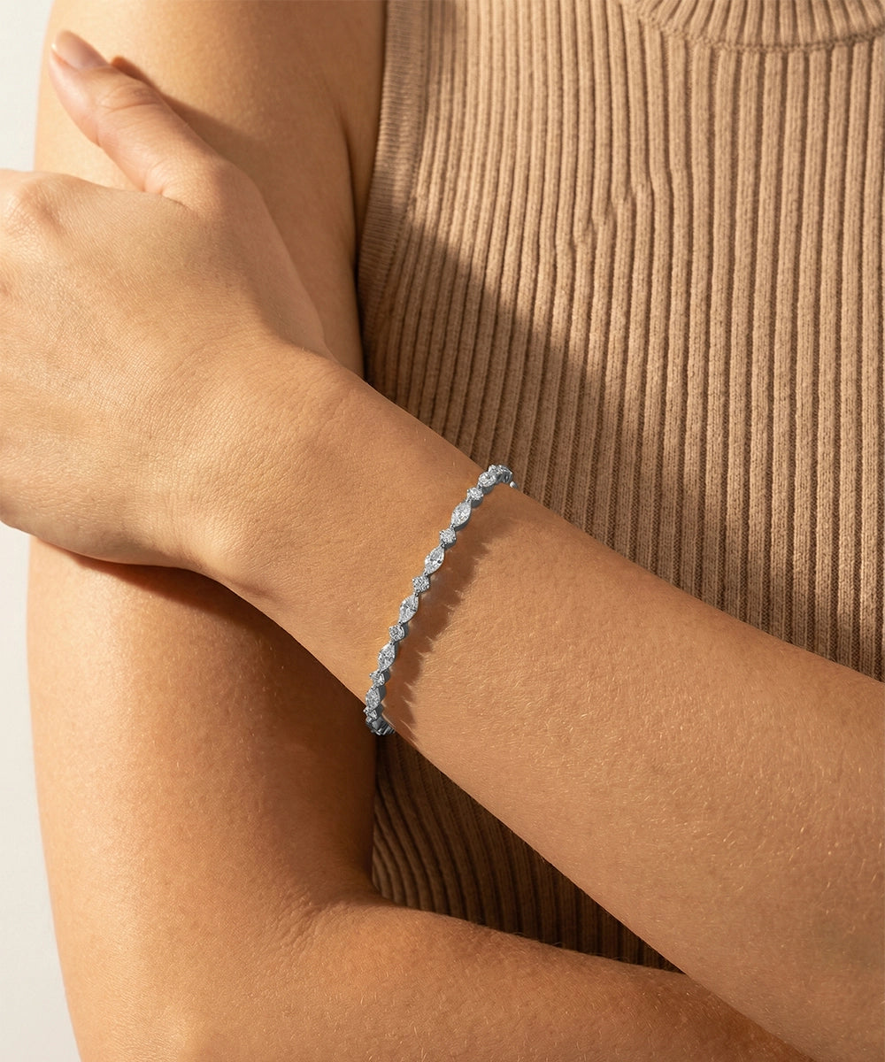 Close-up of a person wearing a blue beaded bracelet on a neutral background
