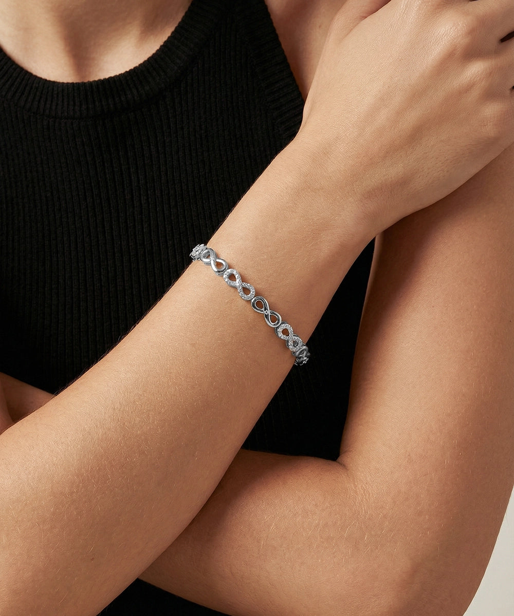 Silver bracelet on a person's wrist with a black background