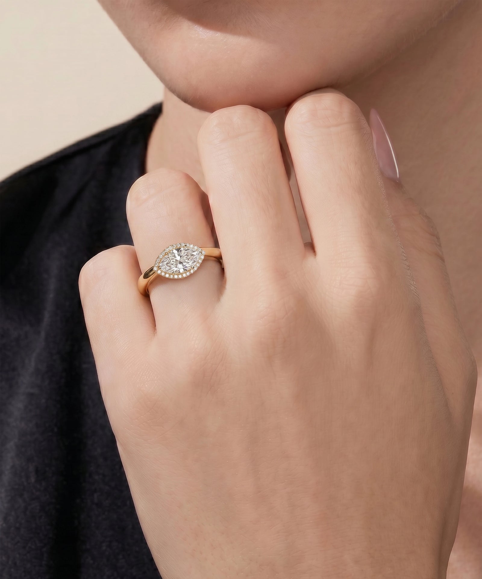 Close-up of a hand wearing a diamond ring on a neutral background