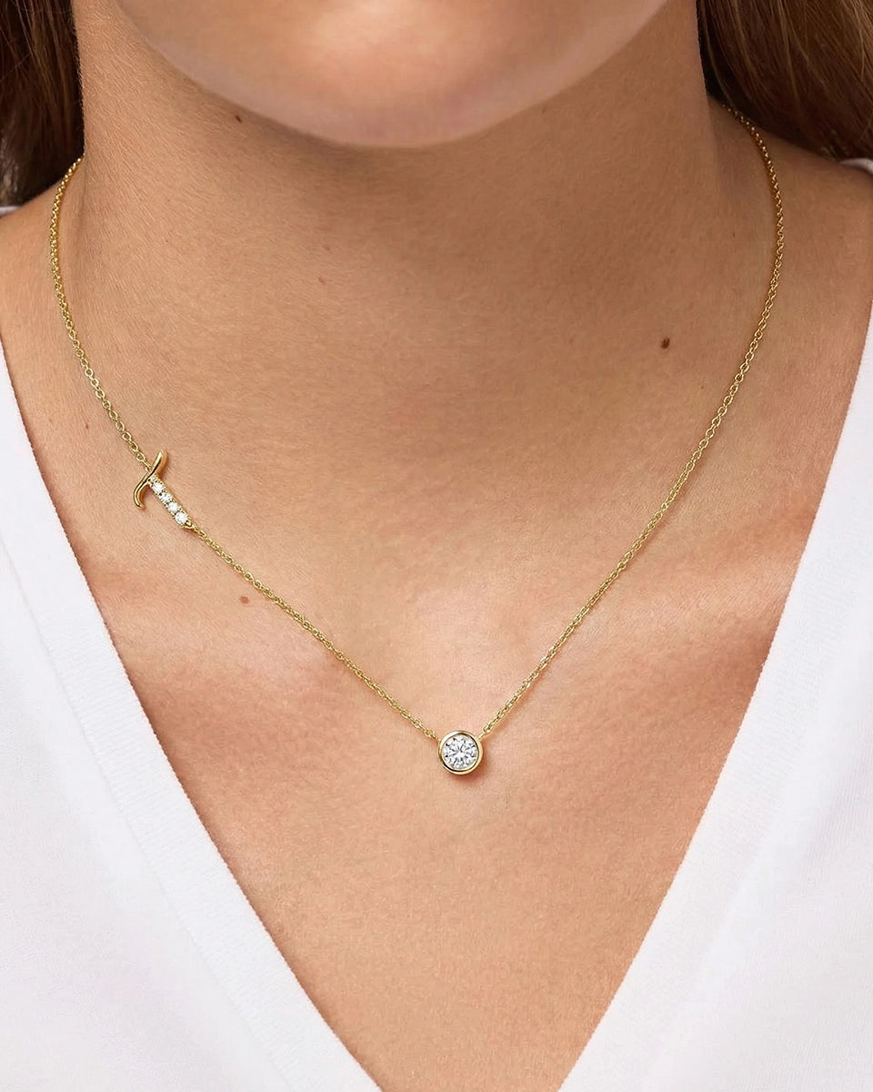 Gold necklace with a round pendant on a person wearing a white top.