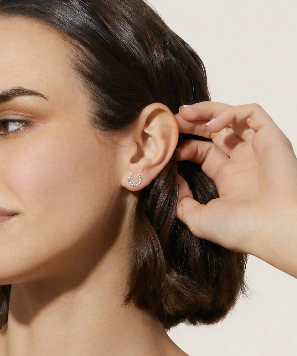 Close-up of a woman wearing a silver earring with a horseshoe design.