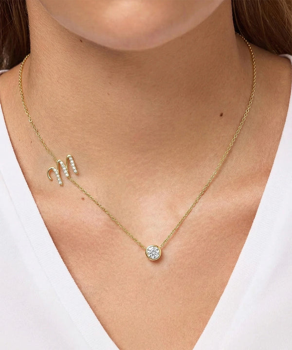 Gold necklace with a round pendant on a person wearing a white top.
