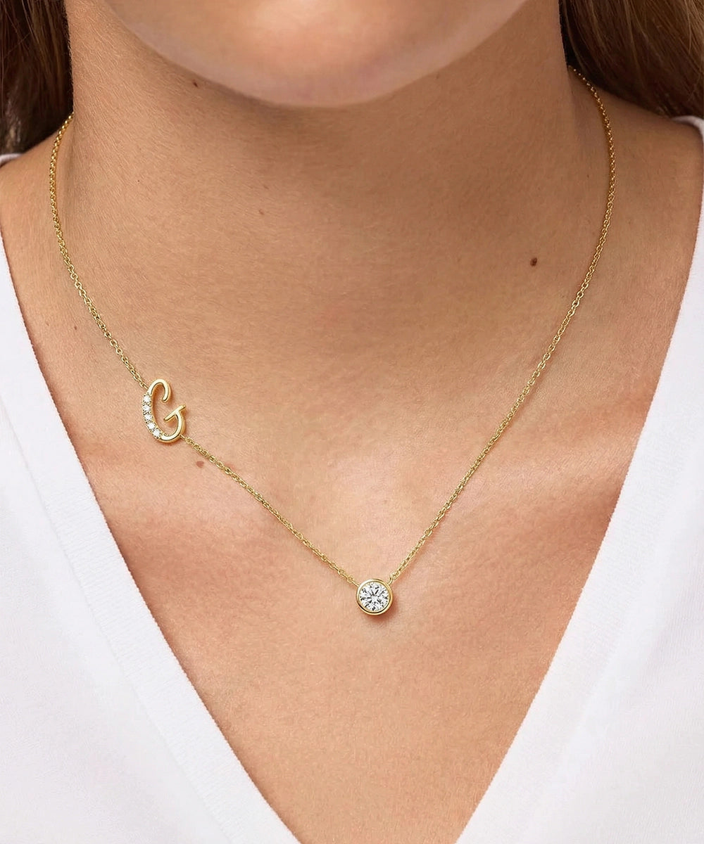 Gold necklace with a small pendant on a person wearing a white top