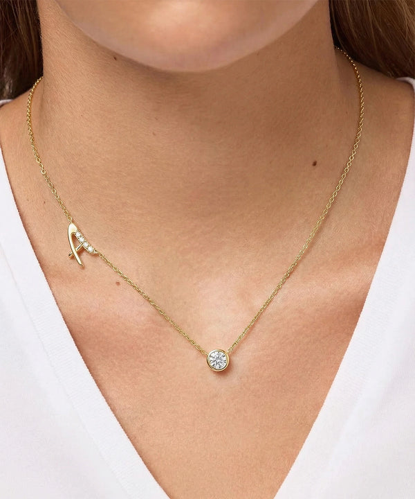 Gold necklace with a round pendant worn by a person against a white background