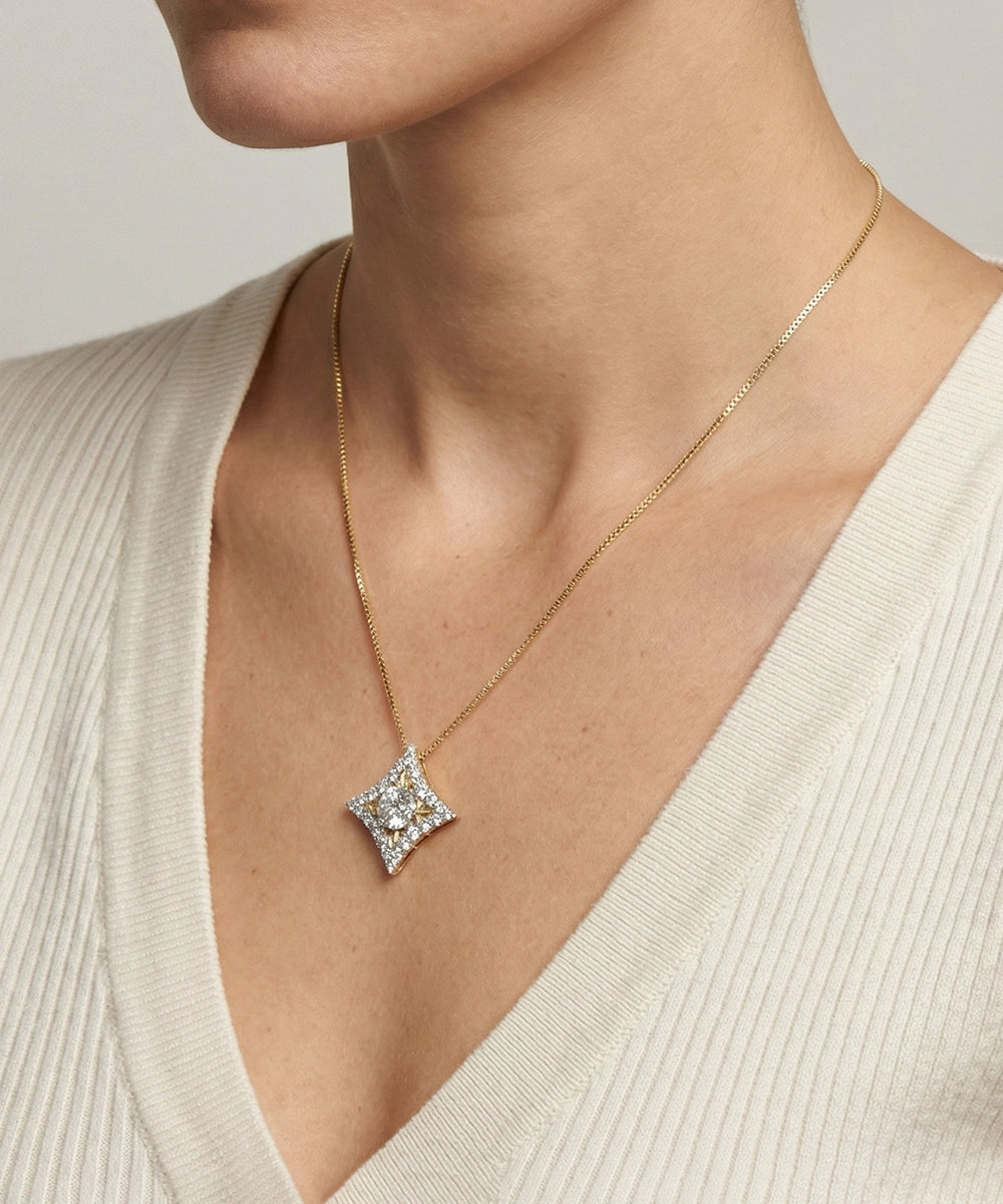 Necklace with a diamond pendant worn by a person in a beige sweater.
