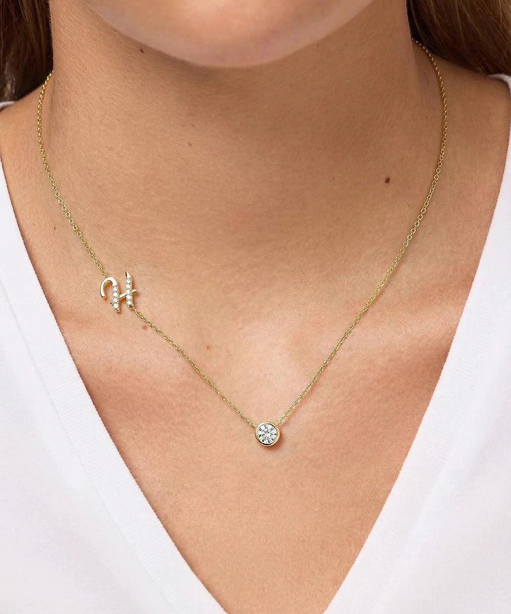 Gold necklace with a small pendant on a person wearing a white top