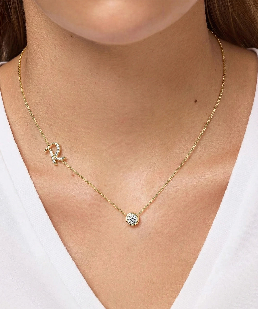 Gold necklace with a small round pendant worn by a person against a white background