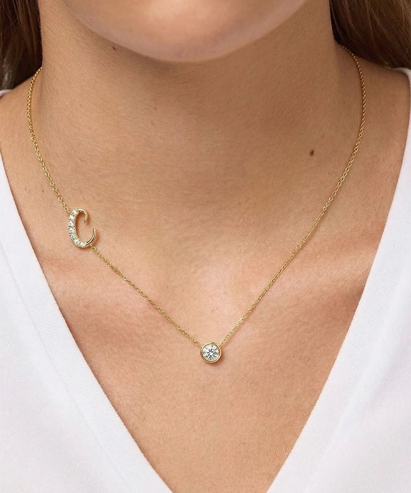 Gold necklace with a pendant on a person wearing a white top