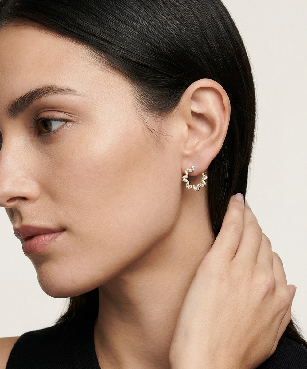 Close-up of a woman wearing a gold hoop earring with a neutral background