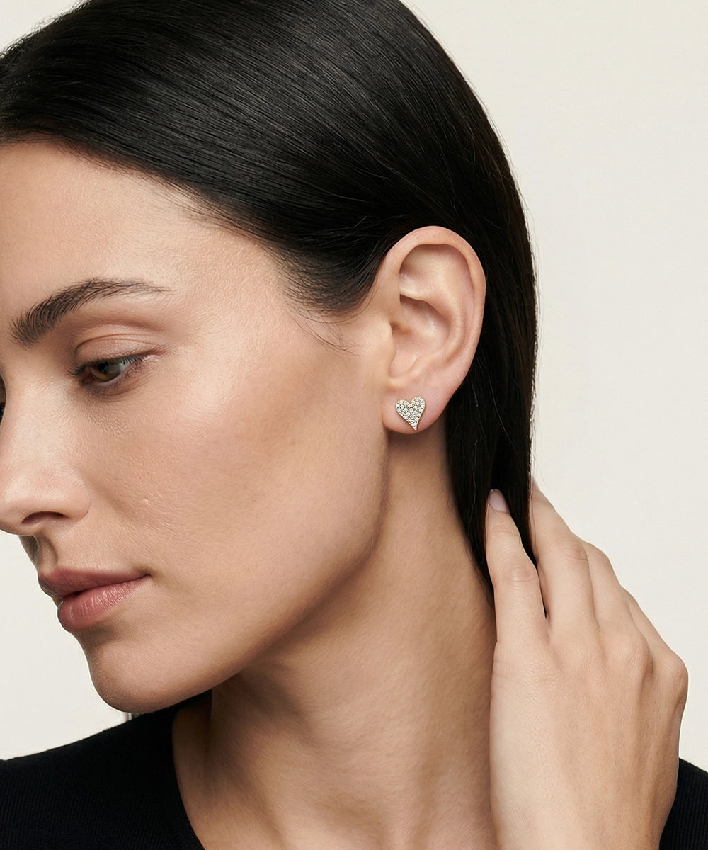 Woman wearing a heart-shaped earring with a neutral background