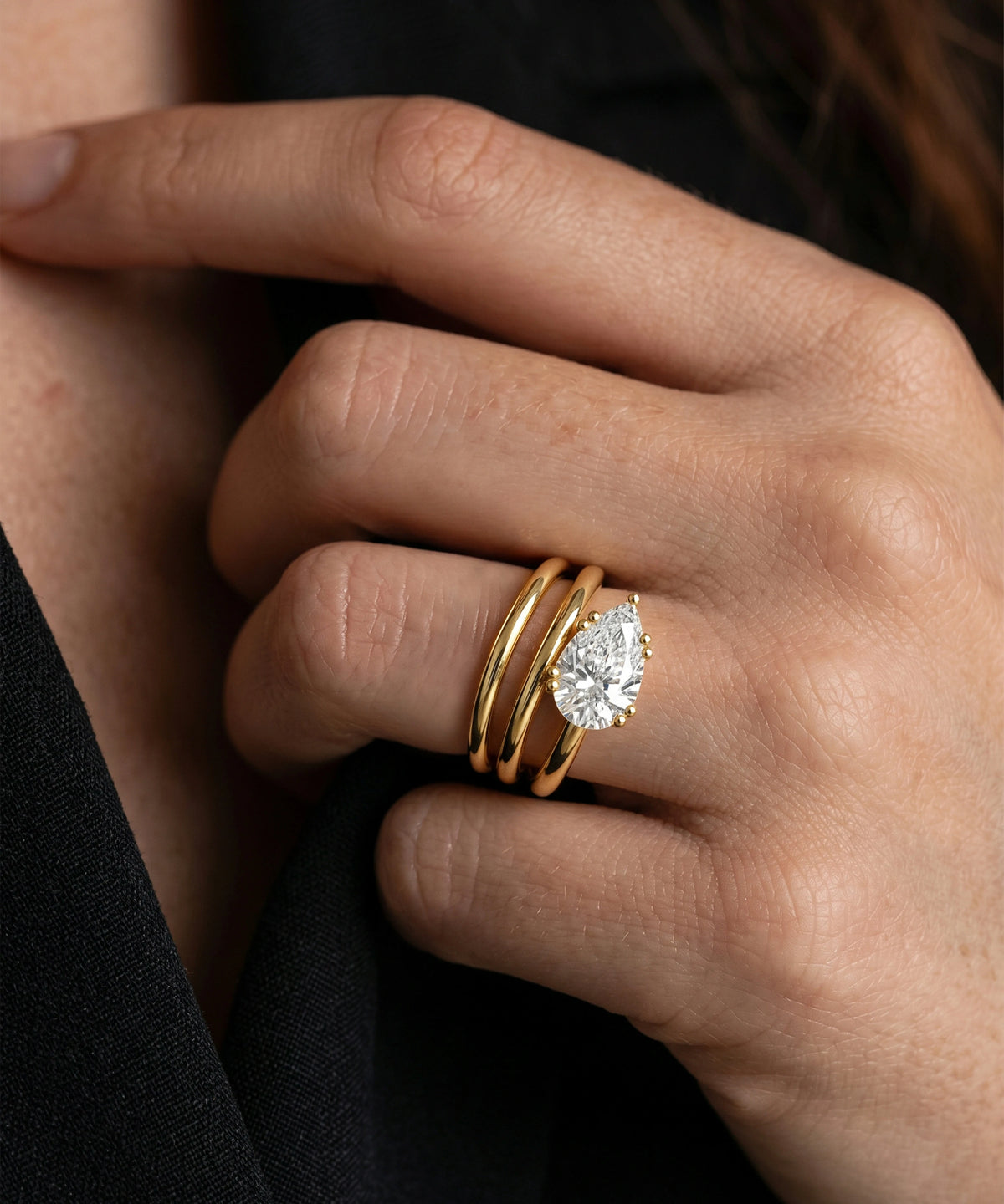 Close-up of a hand wearing two gold rings with diamond accents.