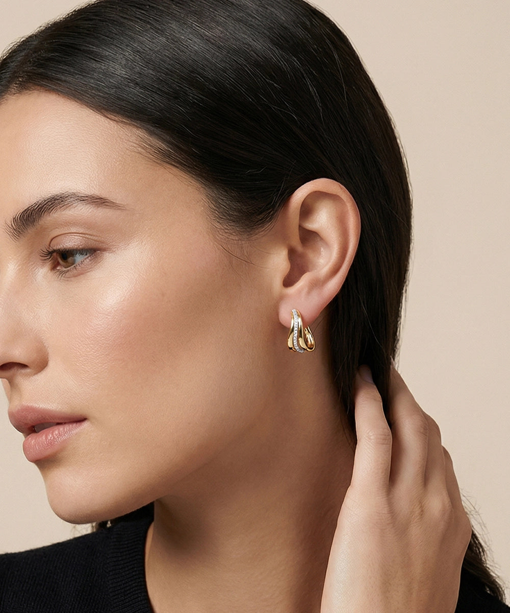 Close-up of a woman wearing gold earrings with a neutral background