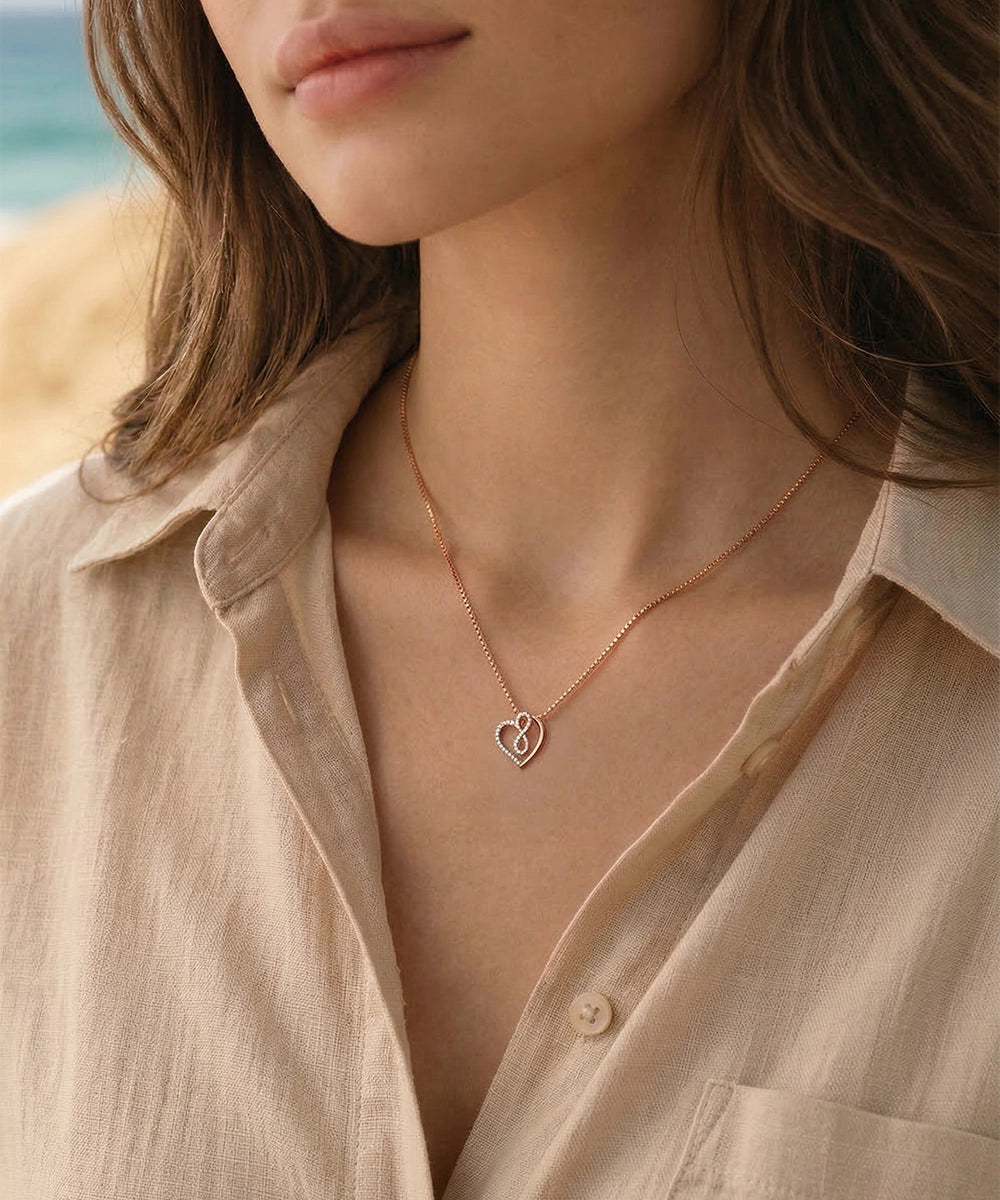 Necklace with a heart pendant worn by a person on a beach.