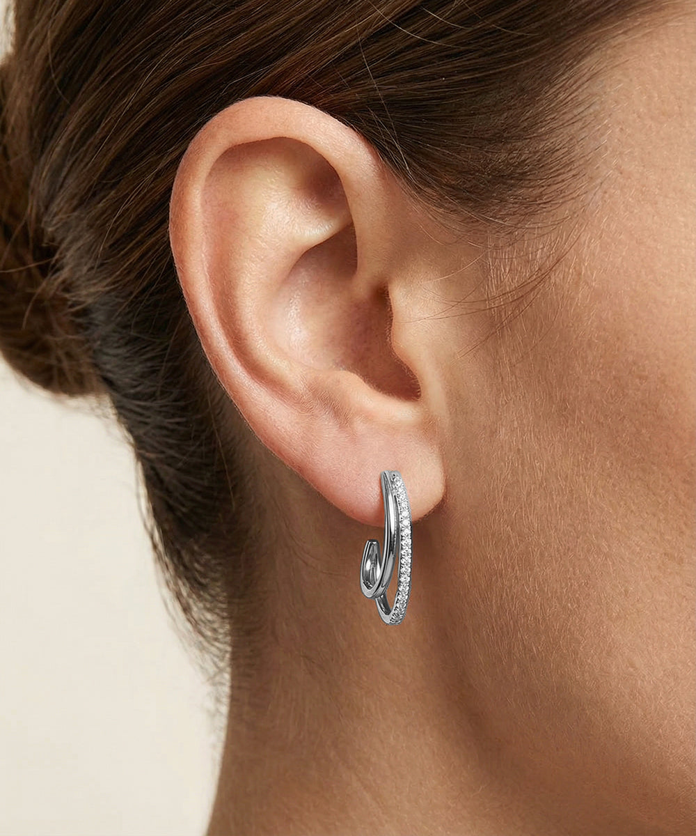 Close-up of an ear wearing a silver hoop earring with a blurred background