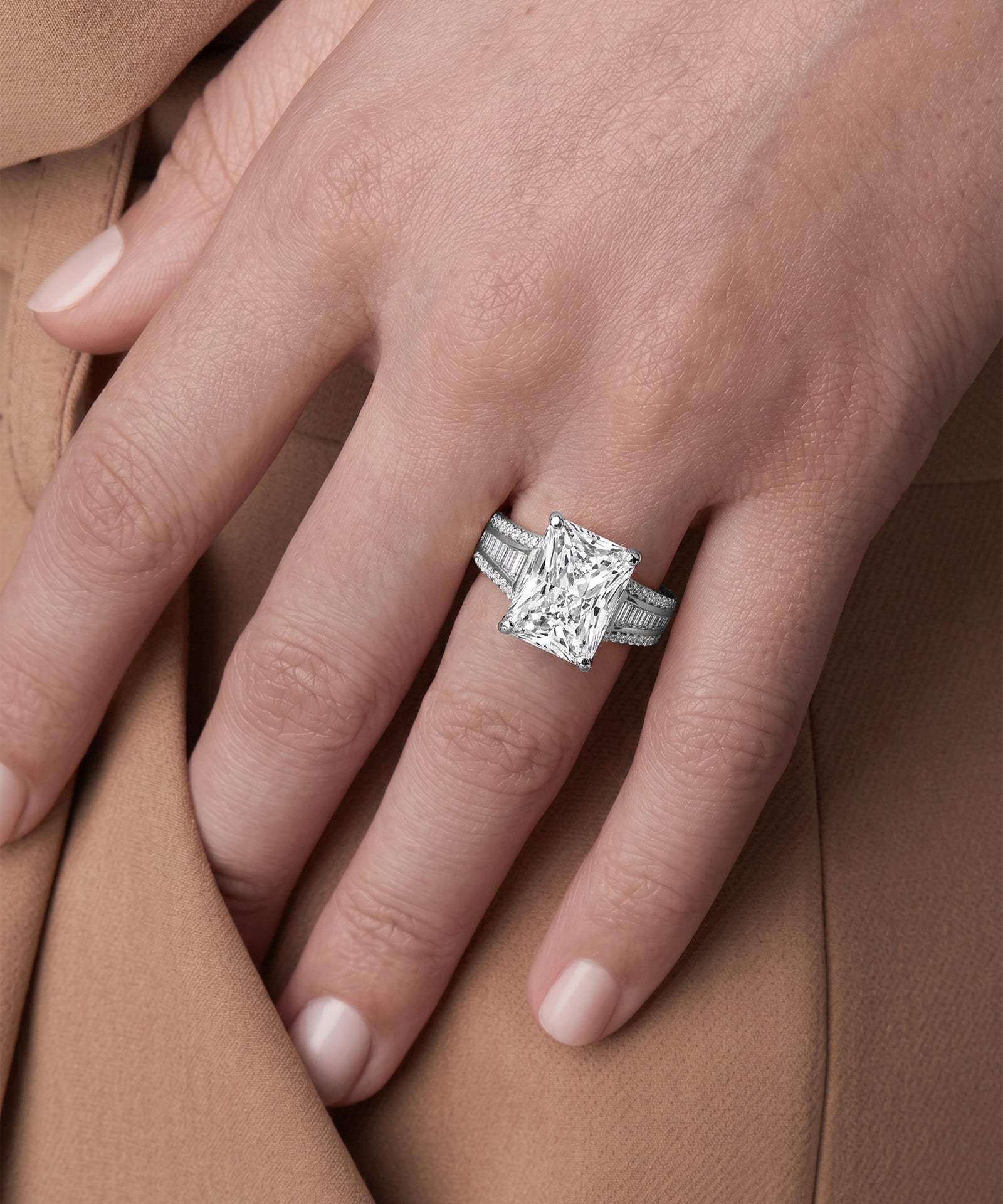 Silver ring with a large diamond on a hand against a brown background