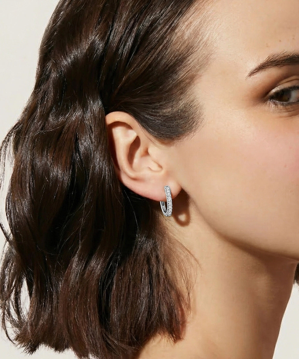Close-up of a woman wearing a silver hoop earring with a neutral background
