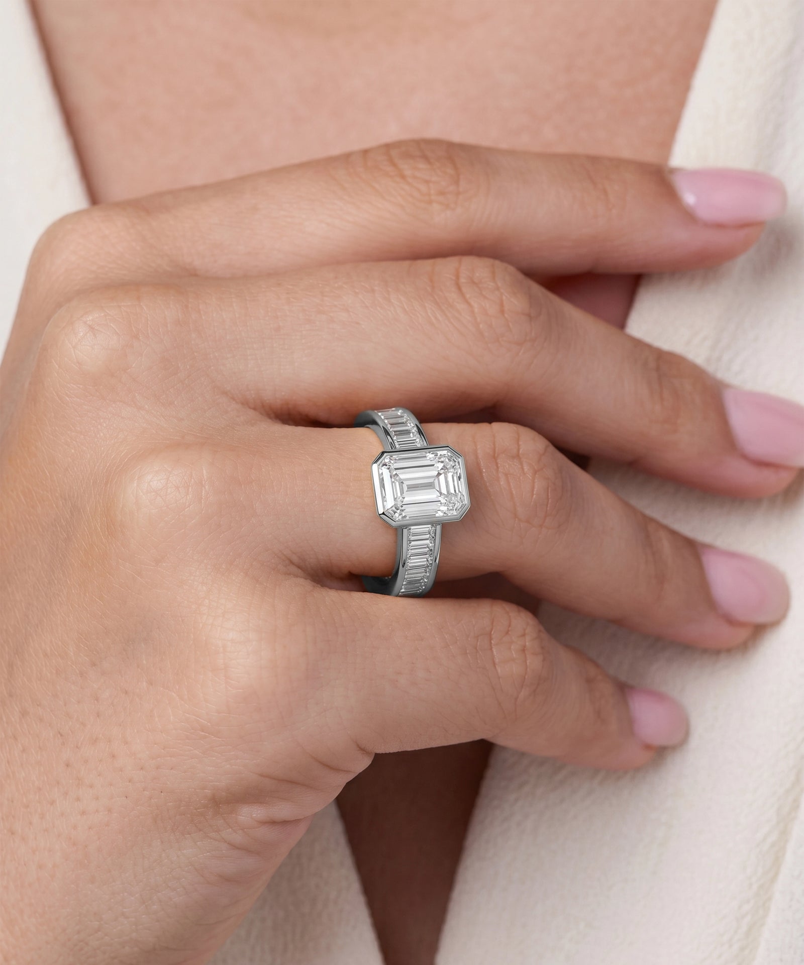 Silver ring with a diamond on a hand against a neutral background