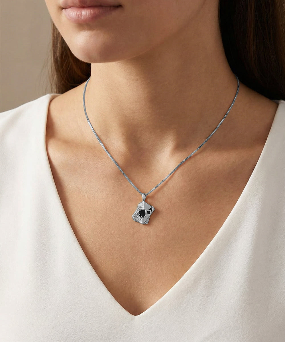 Silver necklace with a pendant worn by a person in a white top against a neutral background