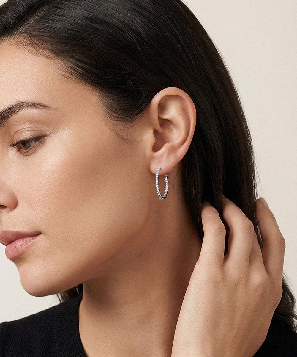 Close-up of a woman wearing a silver hoop earring with a neutral background