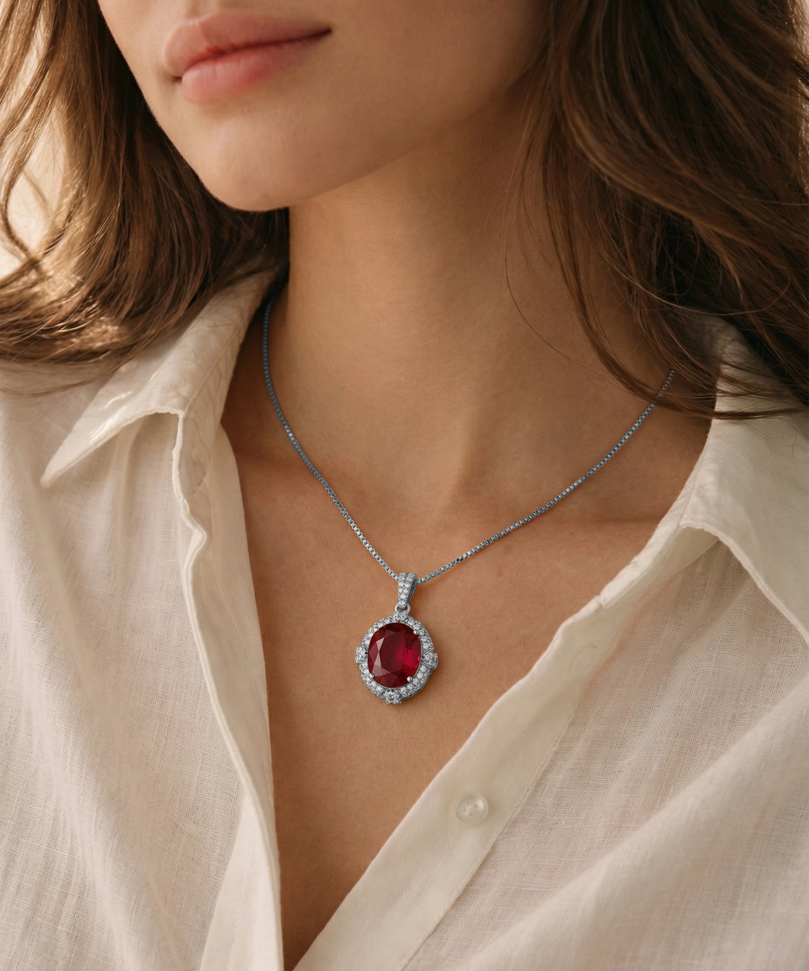 Close-up of a person wearing a necklace with a red gemstone pendant.
