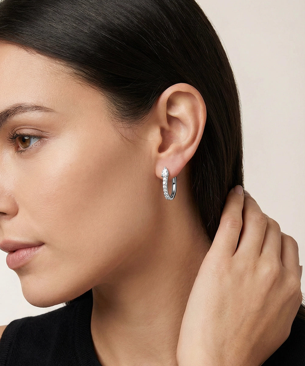 Close-up of a woman wearing silver hoop earrings with a neutral background