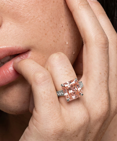 Close-up of a hand wearing a pink gemstone ring with a blurred background - alternate view