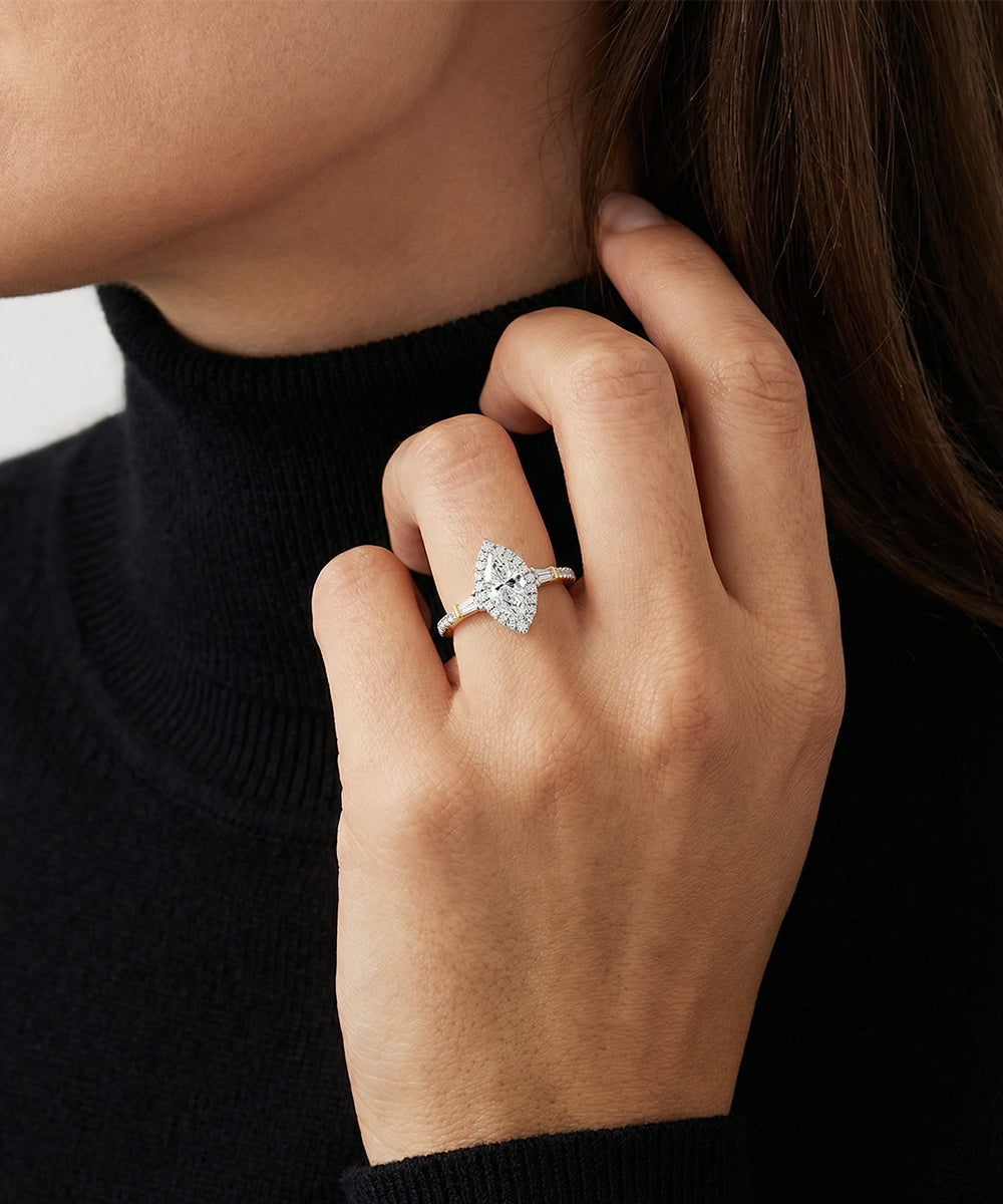 Close-up of a hand wearing a diamond ring against a neutral background