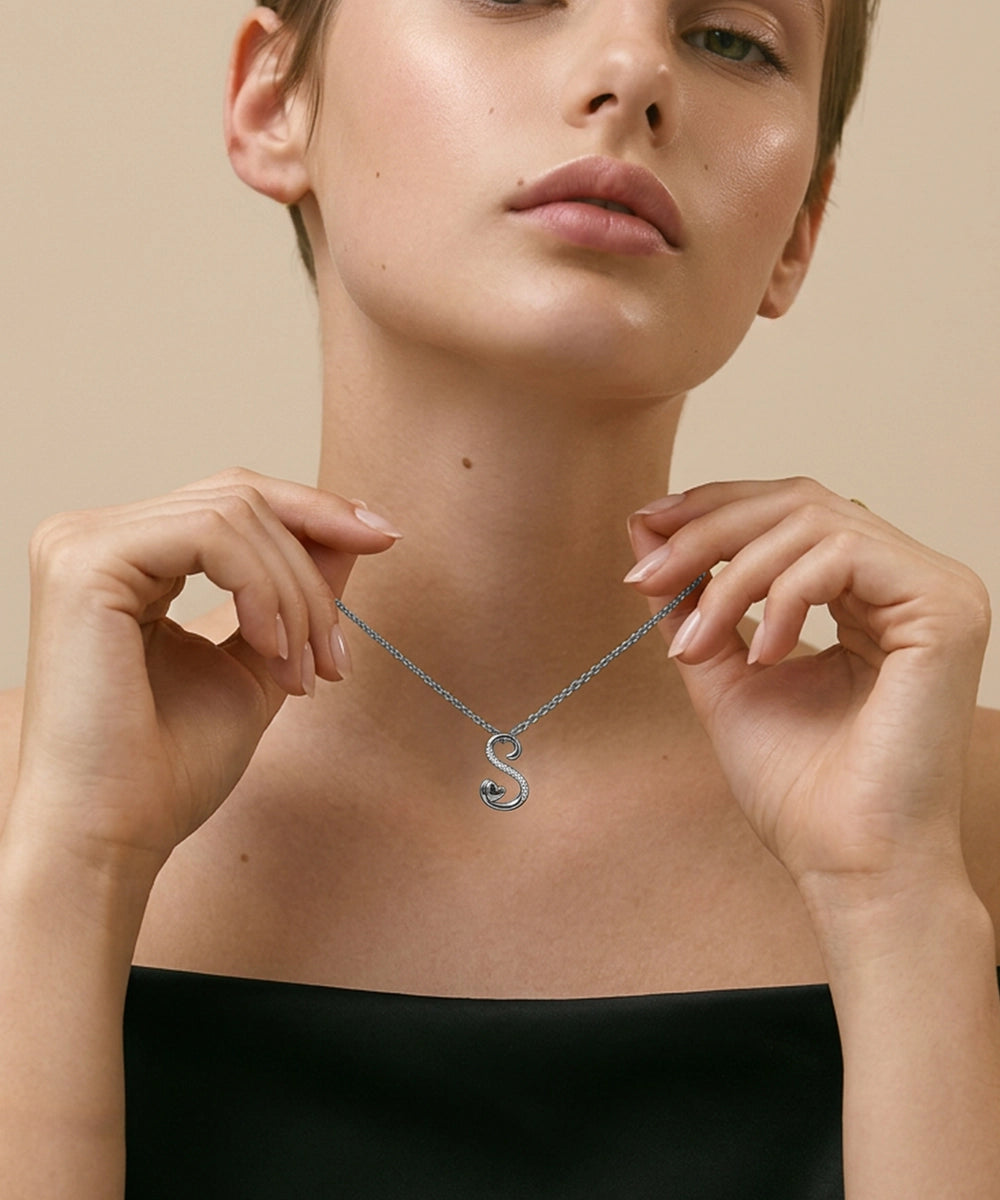 Woman wearing a silver necklace with a heart pendant against a beige background