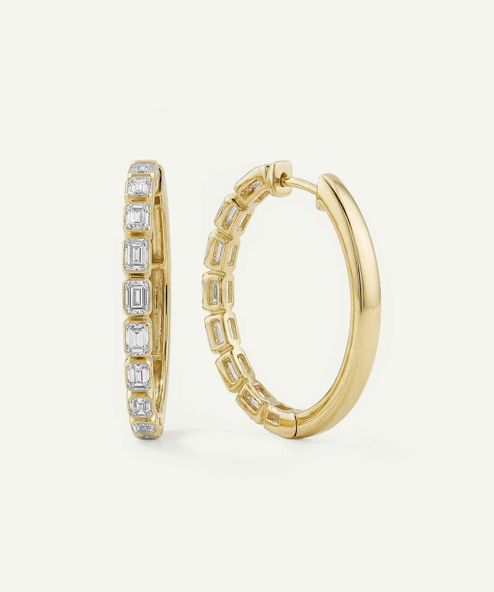 Gold hoop earrings with diamond accents on a light beige background