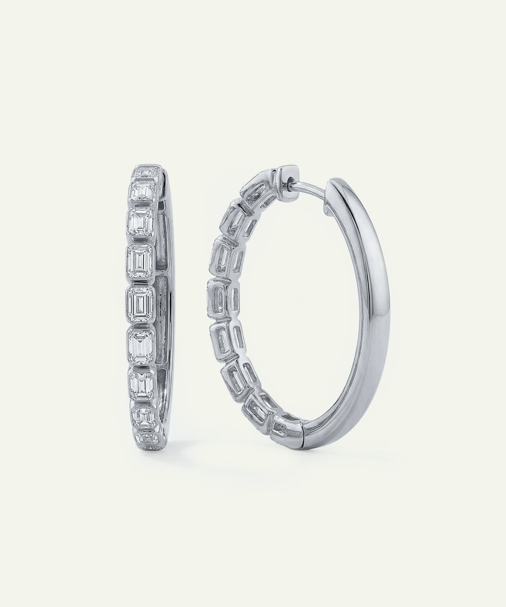 Pair of silver hoop earrings with gemstones on a white background